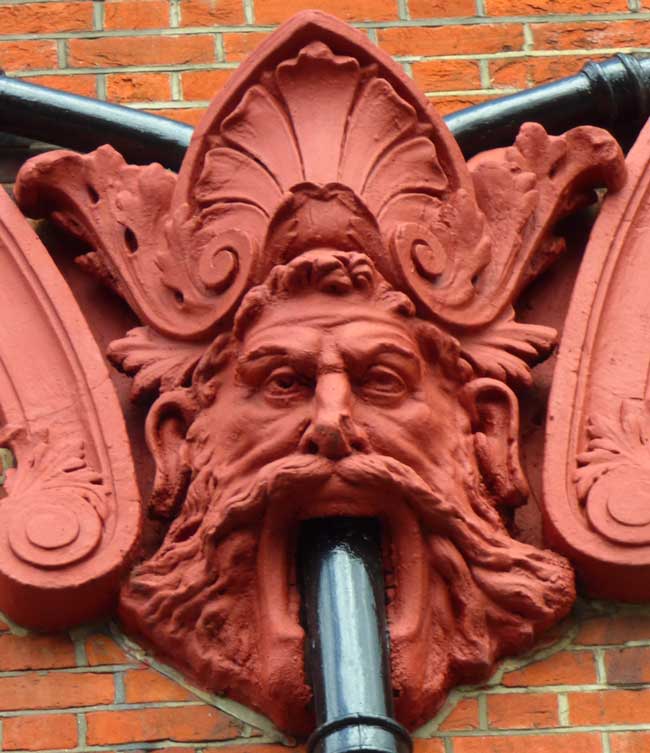 A carved face with a drainpipe coming out of its mouth.
