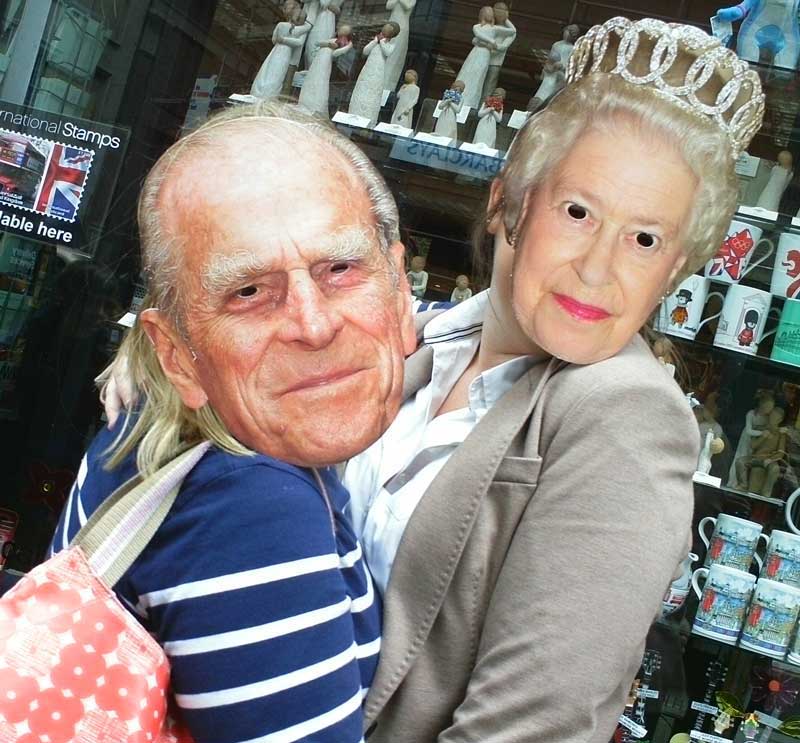 Two team members wearing masks of the Queen and Prince Phillip.