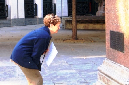 A woman reads a clue on a statue.