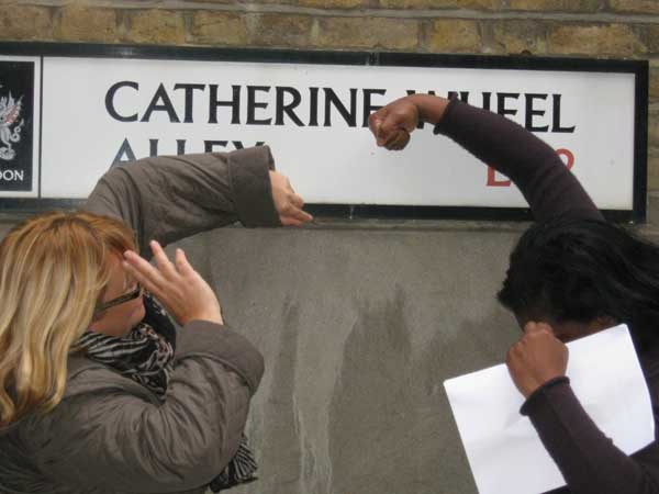 Two ladies making a word for a clue from the street sign for Catherine Wheel Alley.