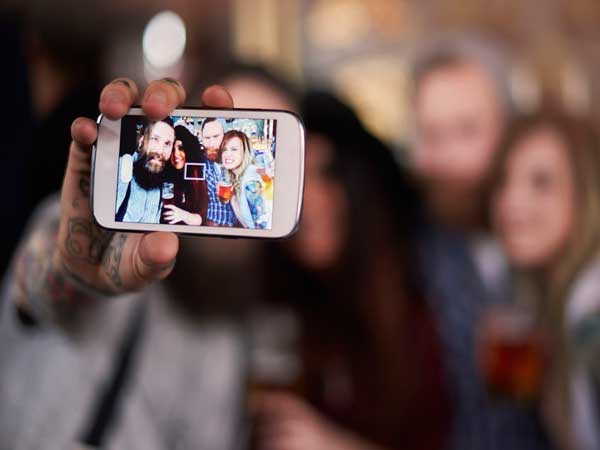 A man's hand holds up a mobile phone on which his team have posed for one of their challenges.