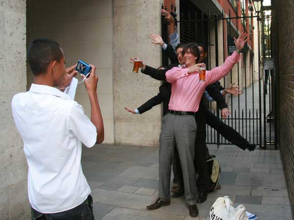 Several men pose as a beer glass tree. They hold pints of beer in their hands.