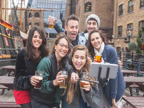 People with beer glasses raised posing outside the Old Thamesside Inn on the Riverside Pubs Treasure Hunt.