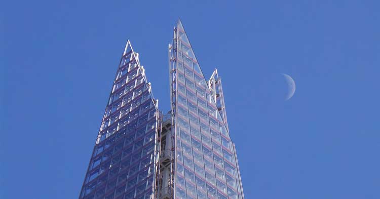 The Shard against a blue sky with the moon to its right.