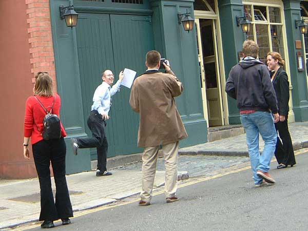 A man balances on one leg whilst being photographed by his team mate.