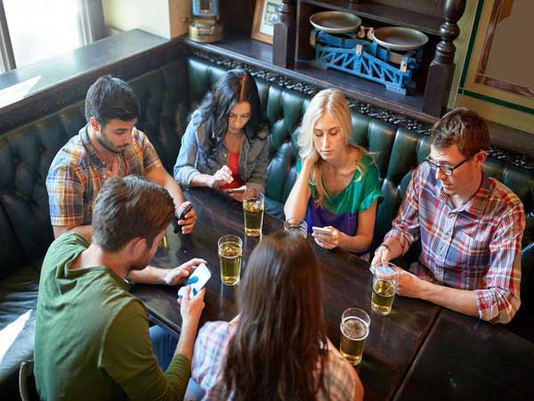 A group of people look up the answer to a clue in a pub on Strand.