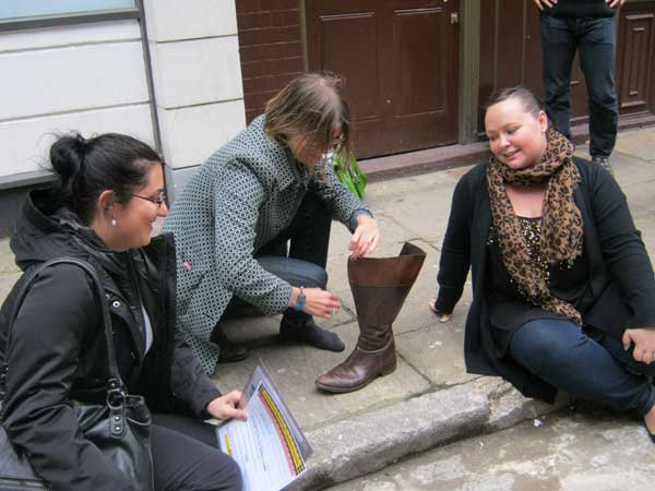 Three members of a team inspect a leather boot.